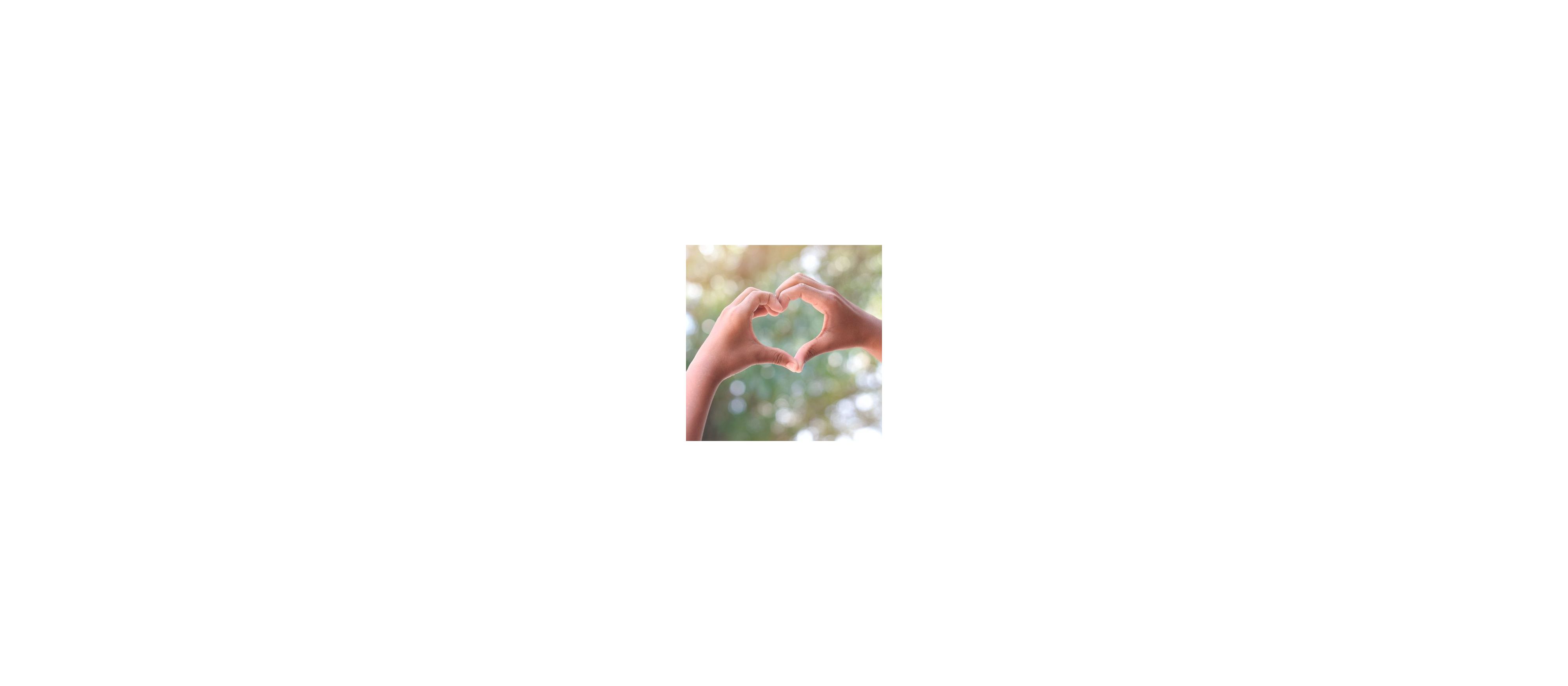 Two hands held up forming a heart shape against a natural background of tree canopies