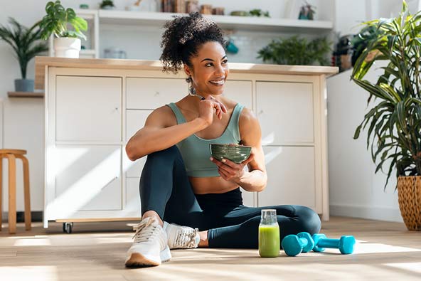 Woman with active wear on is eating a bowl and looks healthy