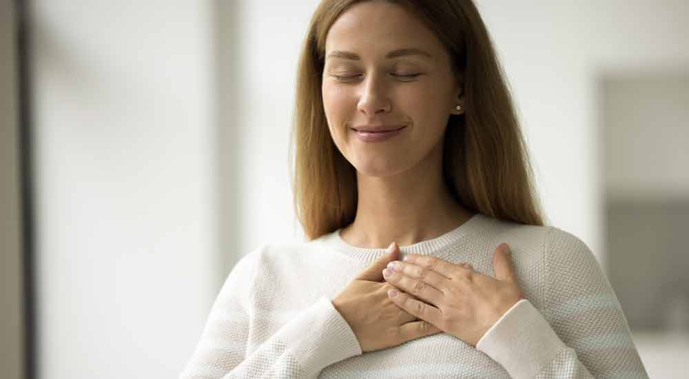 A woman breathing calmly with her hands on her chest