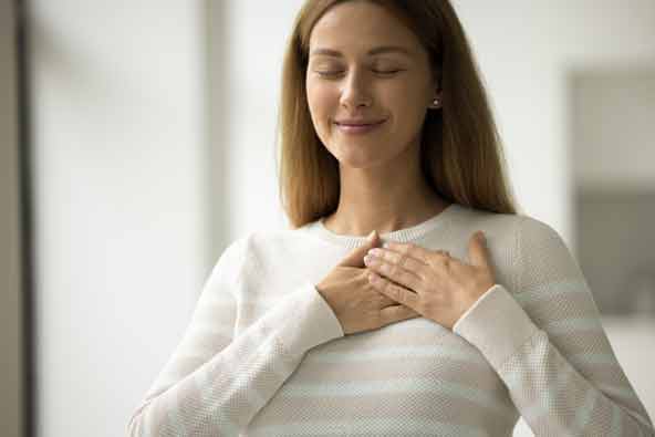 A woman breathing calmly with her hands on her chest