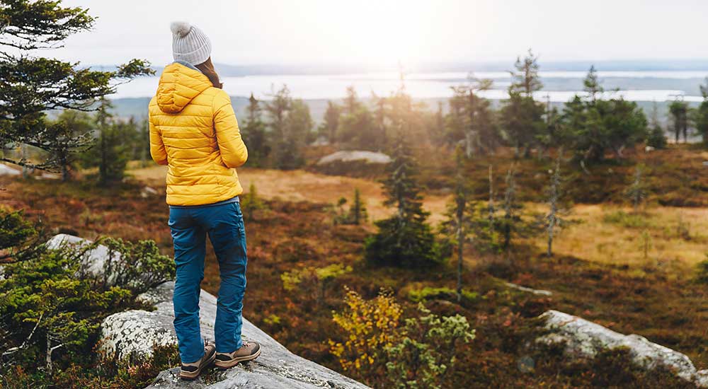 Woman is out for a walk in the forest and looks out over a beautiful view