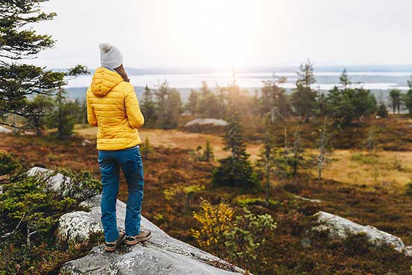 Woman is out for a walk in the forest and looks out over a beautiful view
