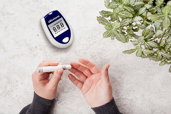 A person pricks their finger with the needle of the ketone meter to measure their ketone level