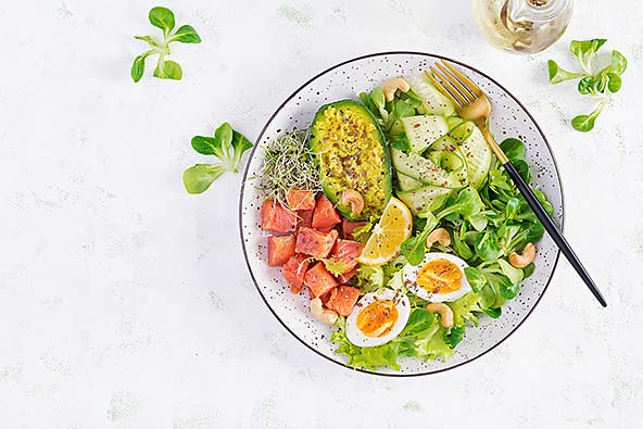 A plate of keto-friendly foods such as avocado, salmon, eggs and vegetables
