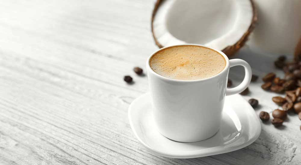 A cup of coffee next to a split coconut