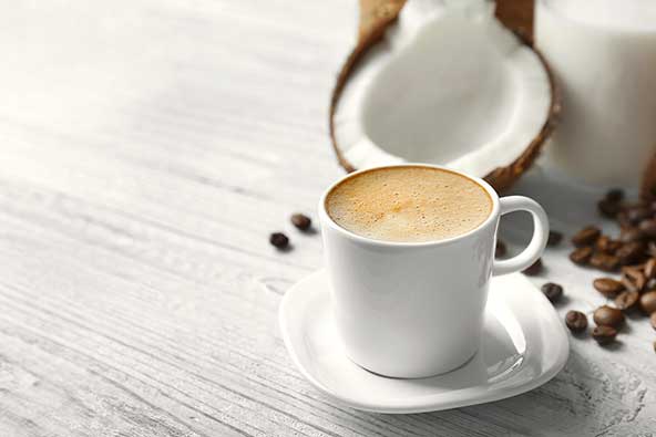 A cup of coffee next to a split coconut