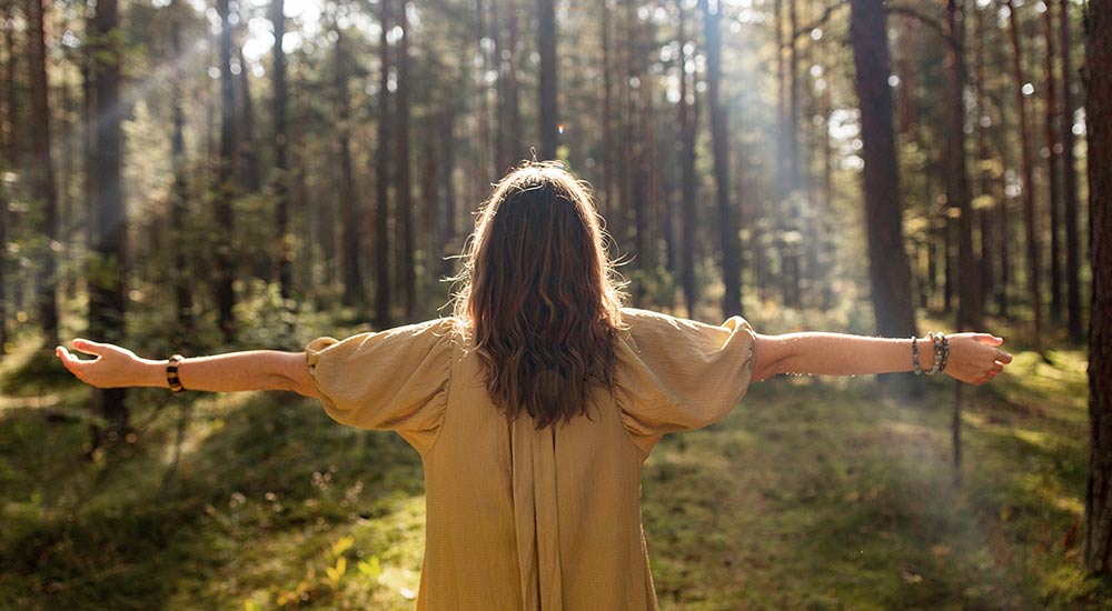 Woman standing in the forest enjoying the sun