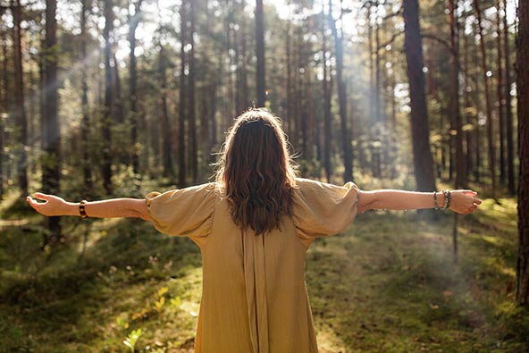 Woman standing in the forest enjoying the sun