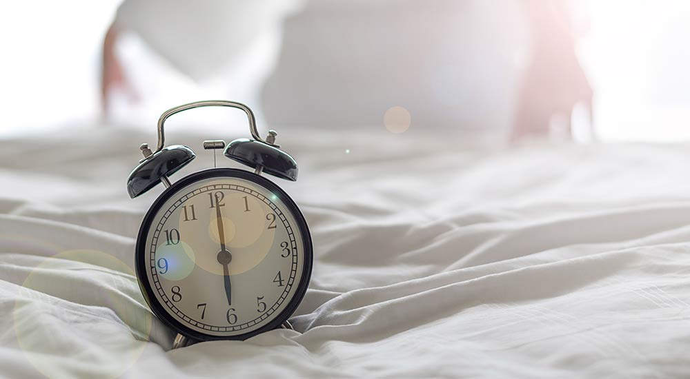Väckarklocka som står på 06.00 i morgonljus