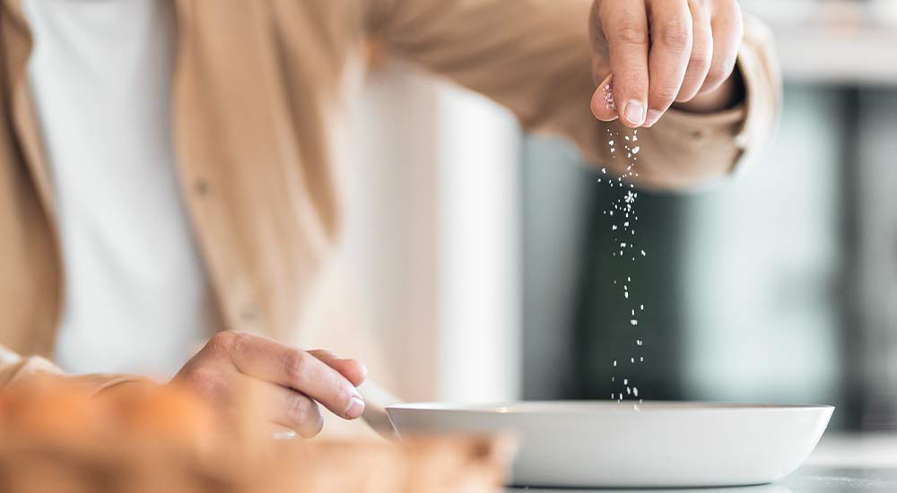 Man som strör salt över sin mat