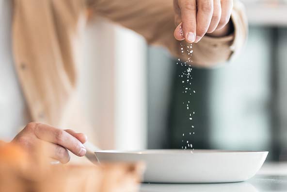 Man som strör salt över sin mat