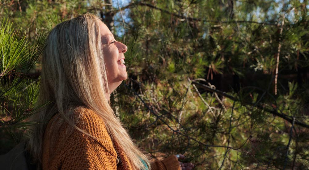 Kvinna på skogspromenad i solen